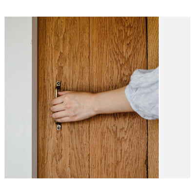 brass handle on wooden door with person holding handle