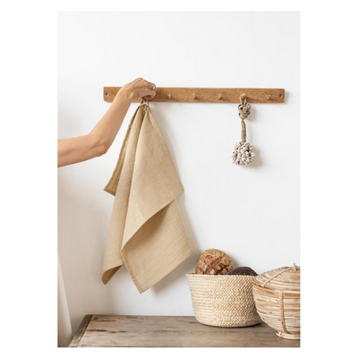 Sandy colored tea towel hanging from a wooden hook